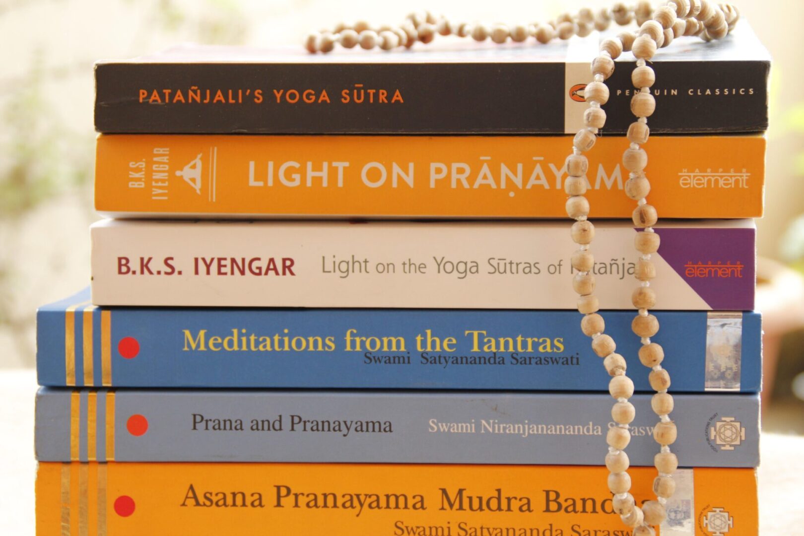 A stack of books with a necklace on top.