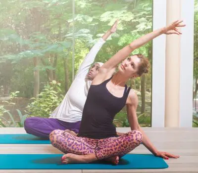 Two women are doing yoga on a mat.