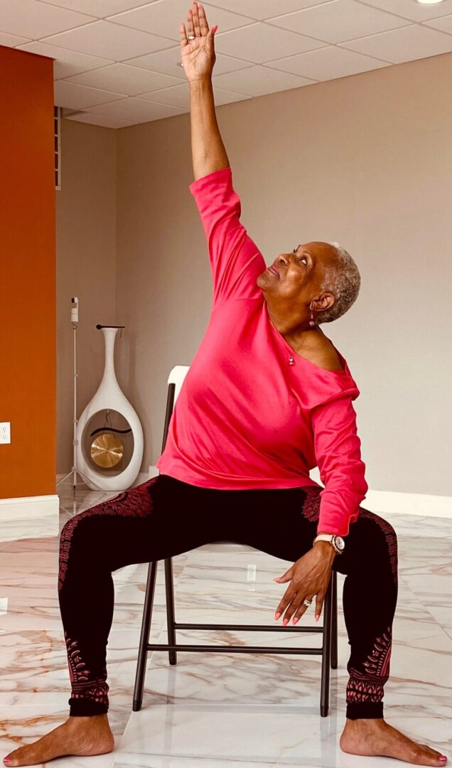 Woman in pink shirt doing chair yoga.