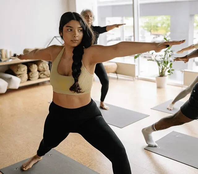 Woman in yoga pose with other people in background.